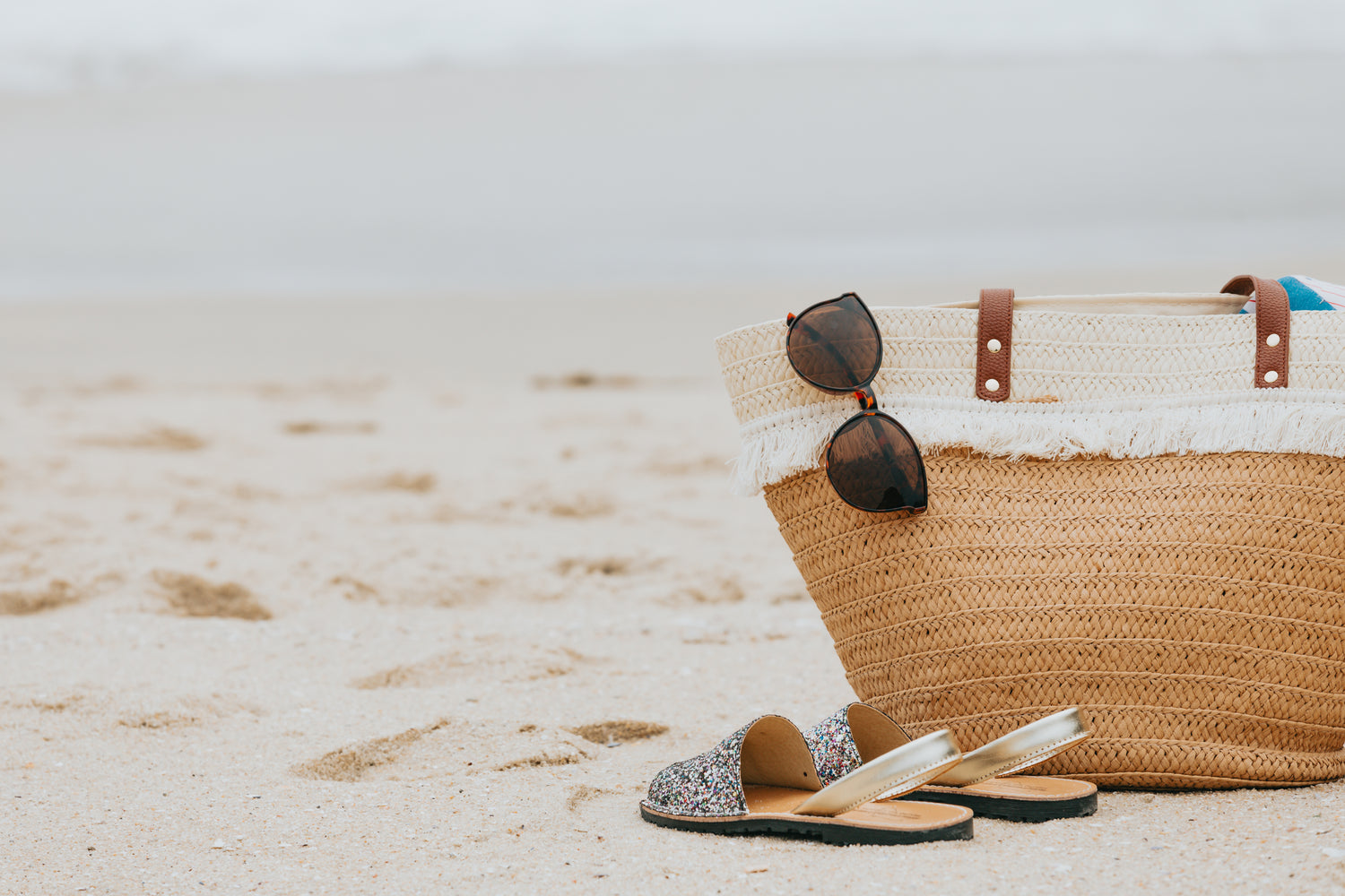 https://bumpnbrew.com/cdn/shop/files/sandy-beach-with-sandals-sunglasses-and-a-beach-bag_1500x.jpg?v=1645808852